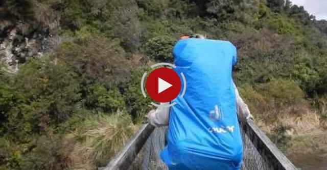 Hikers Crossing A Suspension Bridge